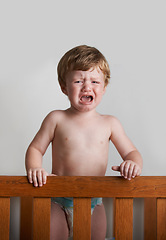 Image showing Sad toddler, crying and portrait of baby in his crib or home with emotional anger or loss in childhood. Problem, trouble and house with a frustrated young male kid, infant or boy with tears or noise