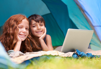 Image showing Kids, portrait and happy with laptop in tent for camping, social media or online movie with diversity in nature. Family, face and siblings or smile outdoor on grass for trip, relax or holiday fun
