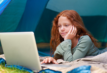 Image showing Child, girl and reading with laptop in tent for camping, social media and online movie with smile in nature. Person, face and kid with vacation outdoor on grass with gaming, relax and holiday fun