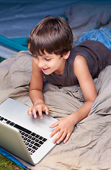 Image showing Kid, relax and laptop to watch cartoon, movie or online games for holiday or vacation. Child, smile and play video with computer on website, streaming or search on internet for elearning with media