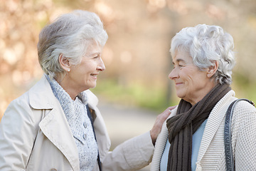 Image showing Senior women, care and touch in park by autumn leaves, together and conversation on retirement in outdoor. Elderly friends, smile or communication on vacation in england, bonding or social in nature