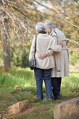 Image showing Senior friends, walk or hugging in nature by autumn leaves, together or care on retirement in park. Elderly women, morning or support on vacation in winter, back or touch in conversation in outdoor