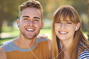 Image showing Couple, smile in portrait and earphones outdoor for music and entertainment, technology and romantic date in park. People listening to radio, podcast or streaming online with happiness in nature