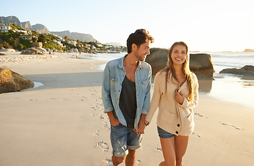 Image showing Couple, holding hands and walking at beach, portrait and smile with love, bonding and kindness on vacation. Man, woman and happy on adventure, holiday and outdoor by sea, water and sand in summer