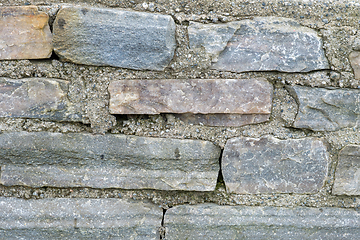 Image showing A detailed look at the varied texture and colors of aged stones in a wall, captured in daylight.