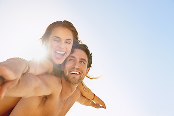 Image showing Happy couple, piggyback and support with blue sky at beach for love, care or enjoying outdoor holiday or weekend. Face of man and woman smile for fun embrace, trust or hug in summer on mockup space