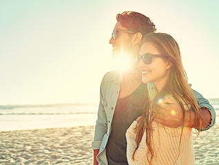 Image showing Sunset, travel and couple hug at a beach with love, adventure and bonding in nature together. Sunrise, lens flare and people embrace at the sea for ocean view, summer and romance on Miami vacation