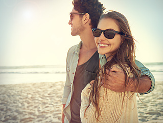 Image showing Couple, sea and sunglasses with hug, smile or care for fashion, eye protection or vacation in summer. Man, woman and embrace in glasses at beach for sun, happy and love by ocean on tropical holiday