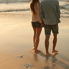 Image showing Beach, sunset and couple holding hands with love, support and relationship security on summer holiday in Portugal. Mockup space, sand and back of partner, soulmate or people on evening walk together