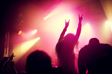 Image showing Rock, concert and people dance at night, event or party at music festival with fans in audience at stage. Crowd, energy and woman with hands in sign for metal, sound or social celebration at rave