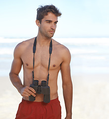 Image showing Man, binoculars and lifeguard on beach for security, emergency or health and safety. Face of young male person in fitness for monitoring, bay watch or patrol by the ocean coast or sea in surveillance