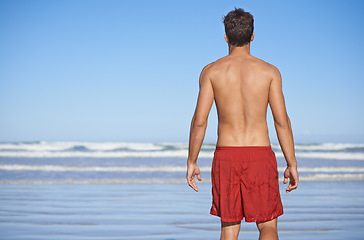 Image showing Man, beach and waves for swimming, workout or outdoor exercise on the ocean coast in summer. Rear view or back of young male person or professional swimmer standing ready at sea on mockup space