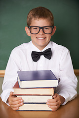 Image showing Boy child, smile and portrait with books, classroom and learning for exam, assessment and studying for knowledge. Student kid, notebook and happy for education, development and glasses at table