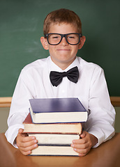 Image showing Boy child, happy and portrait with books, classroom and learning for exam, assessment and studying for knowledge. Student kid, notebook and smile for education, development and glasses at table