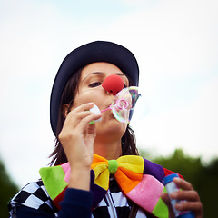 Image showing Clown blowing bubbles at outdoor festival for fun, fantasy and summer adventure in nature. Face of person, street performer or circus character in park with creative color at happy carnival event.