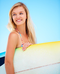 Image showing Surf, board and woman at beach thinking about summer, vacation and holiday mock up space. Happy, face and person outdoor in sunshine on blue background with confidence and a smile for watersports