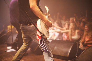 Image showing Music festival, performer and playing guitar for entertainment, night and artist with musical instrument. Back, person and american flag for patriotism at concert, audience and crowd on usa stage