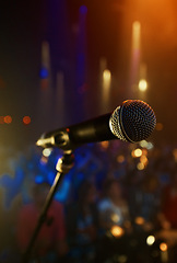 Image showing Microphone, closeup and stage performance in theater with sound equipment for concert or singing. Audio, technology and light in dark room with audience for karaoke, music or event for culture