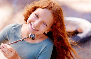 Image showing Young girl, camping and marshmallow in portrait with smile, nature and sweet snack in woods. Red hair, teenager and happiness on face for sugar candy, relax and outdoor on holiday adventure by fire