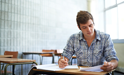 Image showing Student, reading and learning in classroom for education, language development or knowledge in university. Young man writing notes and books for college research, essay paper or course information