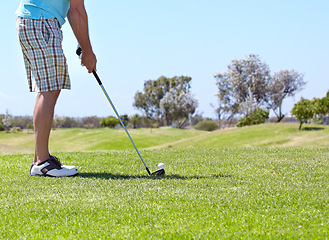 Image showing Man, golf club and ball on green grass, field or lawn for sports, shot or ready to strike on course. Closeup of male person, golfer or player legs in stance with stick for score or point in nature