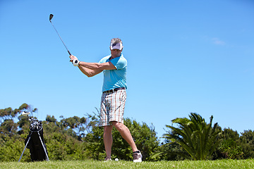 Image showing Senior, man and playing golf on green grass, lawn or field for sports, swing or taking a shot on course. Mature male person, golfer or player hitting ball or strike for goal, score or point in nature