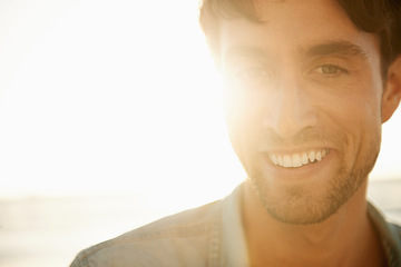 Image showing Man, smile portrait and lens flare at the beach on a holiday and summer vacation outdoor with travel. Happy, sea and male person from California by the ocean with confidence and mockup with sunset