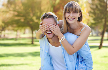 Image showing Piggy back, cover eyes and couple in a park, love and happiness with romance and bonding together. Portrait, man carrying woman and outdoor for fun, playing and cheerful with marriage or summer break