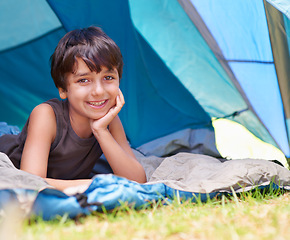 Image showing Boy, kid and camping, relax in tent and summer vacation with travel and happy in portrait outdoor. Rest on sleeping bag, young child with smile and adventure in nature, childhood and recreation