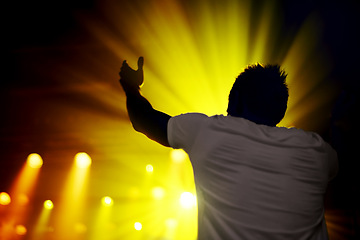 Image showing Music, concert and man in celebration at night, event or cheering with lights from stage. Dark, festival and back of person with energy at nightclub or dancing at show with lighting and shadow