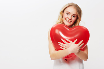 Image showing Woman, portrait and heart balloon for love in studio, happy and valentines day in casual fashion. Model, positive and face by red care symbol, affection and wellness in mockup by white background