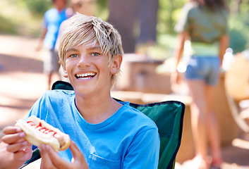 Image showing Eating, hotdog and portrait of kid outdoor in camping chair and relax at barbecue with lunch. Happy, child and hungry for food from bbq in park, woods or forest on holiday or vacation in summer