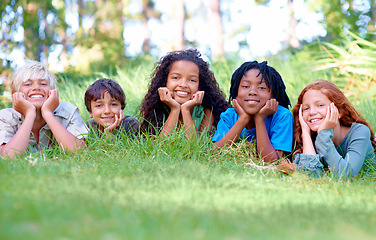 Image showing Nature, smile and portrait of children on grass in outdoor park, field or garden together. Happy, diversity and group of excited young kids relaxing and laying on lawn in woods or forest for summer.