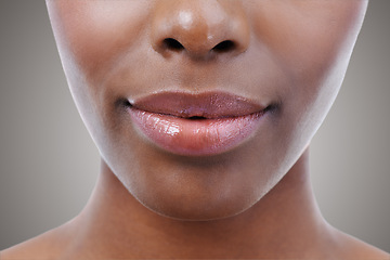Image showing Cosmetics, beauty and lips of black woman on gray background for wellness, skincare and makeup. Dermatology, salon aesthetic and face closeup of person with gloss, lipstick and natural skin in studio