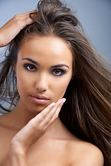 Image showing Woman, portrait and hair in natural beauty, skincare or cosmetics on a blue studio background. Face of young attractive female person, brunette or model with makeup for facial treatment or haircare