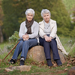 Image showing Senior friends, portrait or outdoor in nature on rock, together or bonding on retirement on holiday. Elderly women, serious or face on trip in countryside, winter or care for person with disability