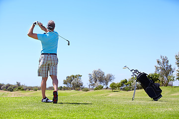 Image showing Senior, man and playing golf on field, lawn or green grass for sports, swing or taking a shot on course. Rear view of person, golfer or player hitting ball, strike or goal to score point in nature