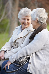 Image showing Senior friends, love and talking by outdoor in nature, together and close bonding on retirement on holiday. Elderly women, smile or looking at face in countryside, happy or social with care on rock