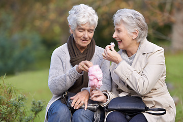 Image showing Elderly women, eating and snack in park with candy floss, happy and together to relax on retirement outdoors. Senior friends, smile and junk food on vacation in countryside and bonding in nature