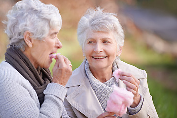 Image showing Senior women, eating and snack in nature with candy floss, together and relax on retirement outdoor. Elderly friends, happy and junk food on vacation in countryside, bonding and social in park