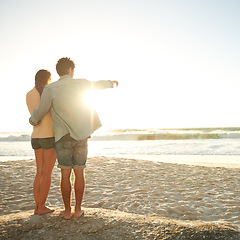 Image showing Beach sunset, hand pointing or couple in nature with hug, support or love. Summer, romance or back of people at sunrise with ocean view, conversation or adventure on vacation, holiday or Florida trip