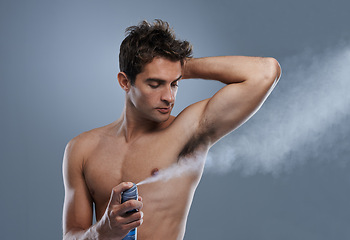 Image showing Man, deodorant and spray for healthy odor in studio or product application for clean smell, hygiene or grey background. Male person, topless and confidence or armpit wellness, care or mockup space