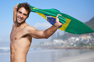 Image showing Man, brazil flag and portrait for happiness at beach, outdoor fun and happy in summer on vacation. Young person, face or holiday by sea in freedom or soccer competition by ocean for travel adventure