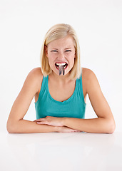 Image showing Crazy, woman and portrait of eating fish, tail or strange food in mouth on white background of studio. Dislike, diet and person with weird seafood, cuisine and disgust for taste of tuna or salmon