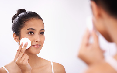 Image showing Woman, cotton pad and face in mirror for makeup, skincare or cosmetics in bathroom at home. Attractive young female person or model smile for grooming skin, facial treatment or removal in reflection