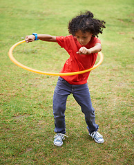 Image showing Child, playing and hula hoop on field on vacation, green grass and sunshine with happiness in city. Young boy, mexican and game on playground, summer holiday and leisure with wellness in urban town