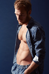 Image showing Fashion, thinking or model with abs in studio on a blue background wearing an open unbuttoned shirt. Ginger man, body or handsome male person posing on color wall for masculine style with six pack