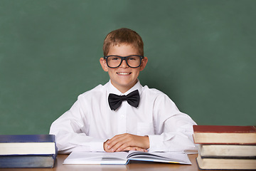 Image showing Boy child, books and school in portrait with smile, information and knowledge with pride in classroom. Student kid, happy and excited for education, learning and development by chalkboard at desk