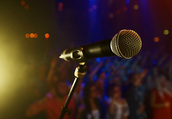 Image showing Closeup, microphone and stage performance in theater with audience and sound equipment for concert or singing. Audio, technology and light in dark room with crowd for open mic, karaoke or music event