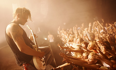 Image showing Guitar, musician and concert crowd at stage with man in performance of rock or metal music. Festival, event and audience of people in celebration of talent in theater at night with light and energy